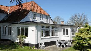 Ein zweistöckiges weißes Gebäude mit rotem Ziegeldach, einer Terrasse mit Außenbestuhlung und einem Schild mit der Nummer 306.