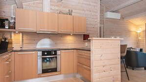 Eine moderne Küche mit Holzschränken, einem eingebauten Backofen und einem Essbereich mit Tisch und Stühlen.