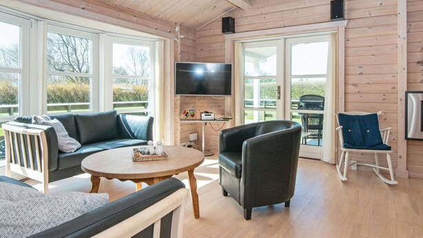 Ein gemütliches Wohnzimmer mit einer Couch, einem runden Tisch, einem Fernseher und einem Schaukelstuhl.