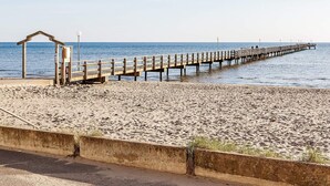 A beach with a wooden pier extending into the sea, a small shelter, and a concrete barrier. - 6 Person Holiday Home in Falkenberg (Falkenberg)
