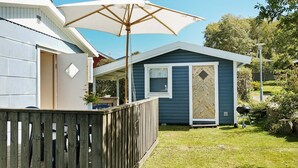 A single-story mobile home with a porch, a wooden deck, and a barbecue grill in the yard. - 6 Person Holiday Home in Falkenberg (Falkenberg)
