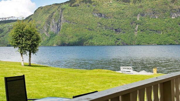A lakeside view with a wooden deck, a table, and a chair. - 4 Person Holiday Home in Utvik (Stryn)