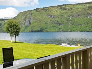 A lakeside view with a wooden deck, a table, and a chair. - 4 Person Holiday Home in Utvik (Stryn)