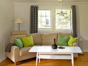 A living room with a beige sofa, green pillows, a white table, and a lamp. - 4 Person Holiday Home in Utvik (Stryn)