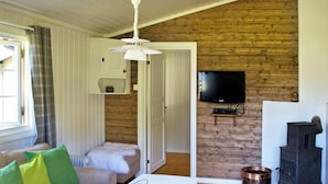 A cozy living room with a sofa, a coffee table, and a television. There is a wooden wall and a fireplace. - 4 Person Holiday Home in Utvik (Stryn)