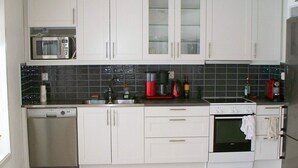 A modern kitchen with white cabinets, a microwave, a coffee maker, and a stove. - Holiday Home in Ronneby (Ronneby)