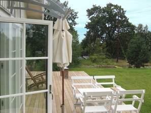 An outdoor deck with white wooden furniture and a covered area. - Holiday Home in Ronneby (Ronneby)