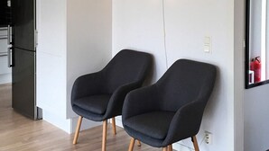 A modern kitchen with a black refrigerator, two dark armchairs, and a wall-mounted light fixture. - Holiday Home in Ronneby (Ronneby)