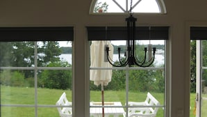 A room with large windows, a chandelier, and a view of a deck with outdoor furniture. - Holiday Home in Ronneby (Ronneby)