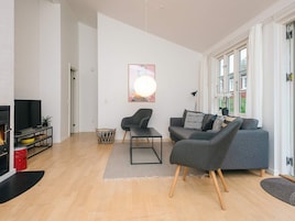 Una sala de estar moderna con un sofá gris, un sillón negro y un televisor sobre un mueble negro.