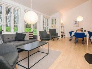 Una sala de estar moderna con un sofá, sillas, una mesa de comedor y un ventanal grande.
