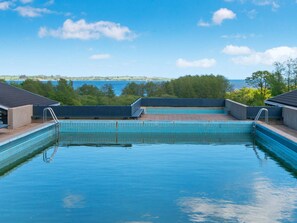 Una piscina con agua cristalina azul, rodeada por una terraza con escalones que bajan a la piscina.