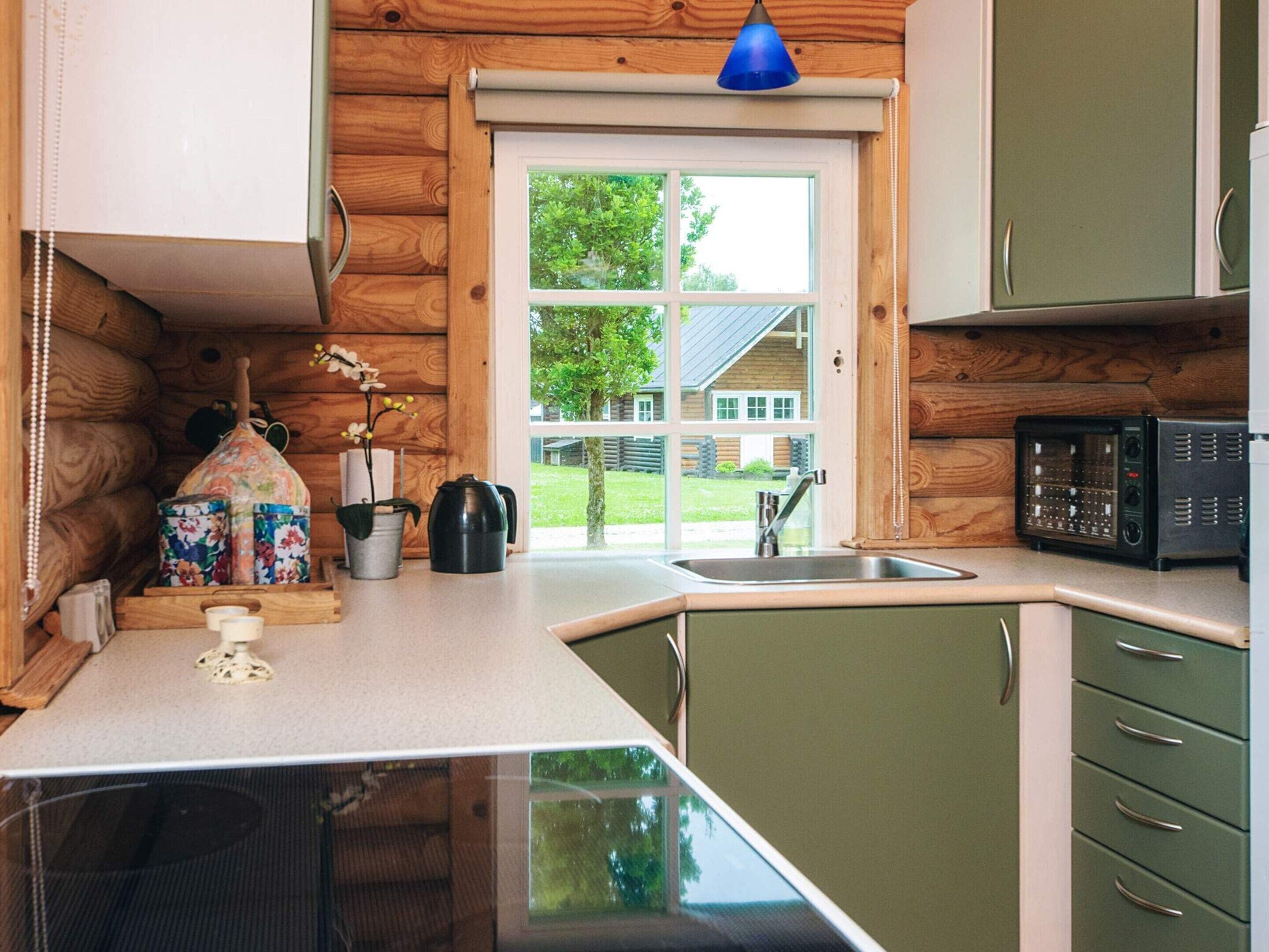 Una cocina pequeña con paredes de madera, una ventana y un microondas.