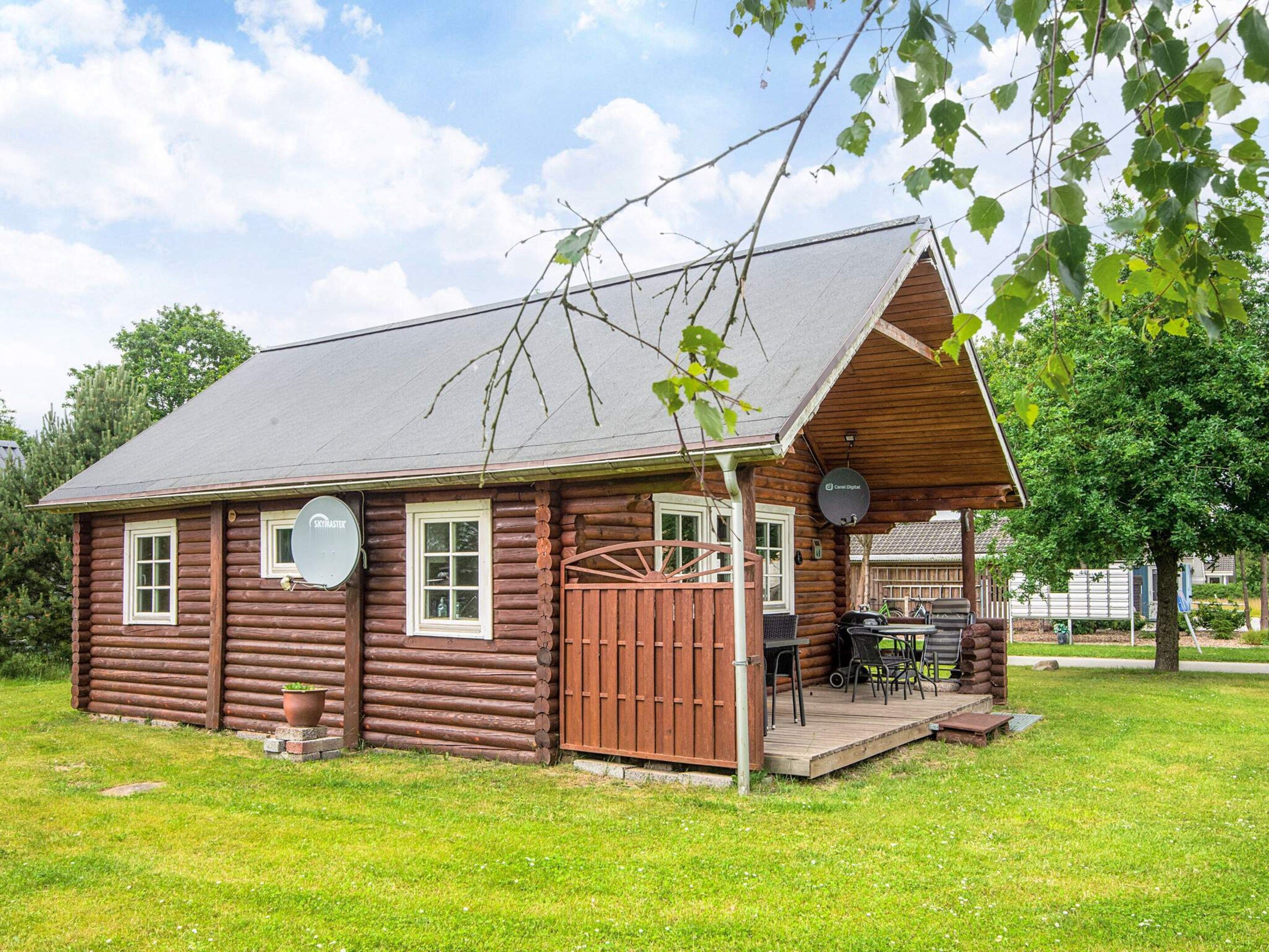 A rustic log cabin with a porch, satellite dishes, and outdoor seating.