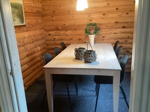 A wooden cabin interior with a white table, black chairs, and two black lanterns. - Cozy Holiday Home in Hovborg near Community Area (Hovborg)