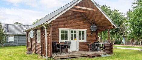 A log cabin with a porch, a dining table, and chairs.