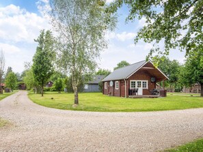 A wooden cabin with a porch, a gravel driveway, and surrounding trees. - Cozy Holiday Home in Hovborg near Community Area (Hovborg)
