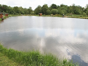 A calm pond with wooden structures and a grassy bank.