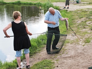 A person fishing by a calm body of water with a net and a fishing rod. - Cozy Holiday Home in Hovborg near Community Area (Hovborg)
