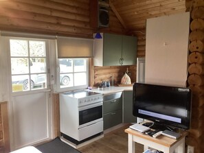 A compact kitchen with a stove, oven, and a television on a stand. - Cozy Holiday Home in Hovborg near Community Area (Hovborg)