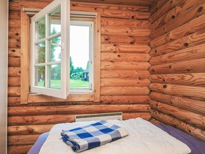 A log cabin room with a bed, a window, and a view of a house and trees outside. - Cozy Holiday Home in Hovborg near Community Area (Hovborg)