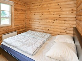 Habitación de una cabaña de madera con cama, ventana y radiador.