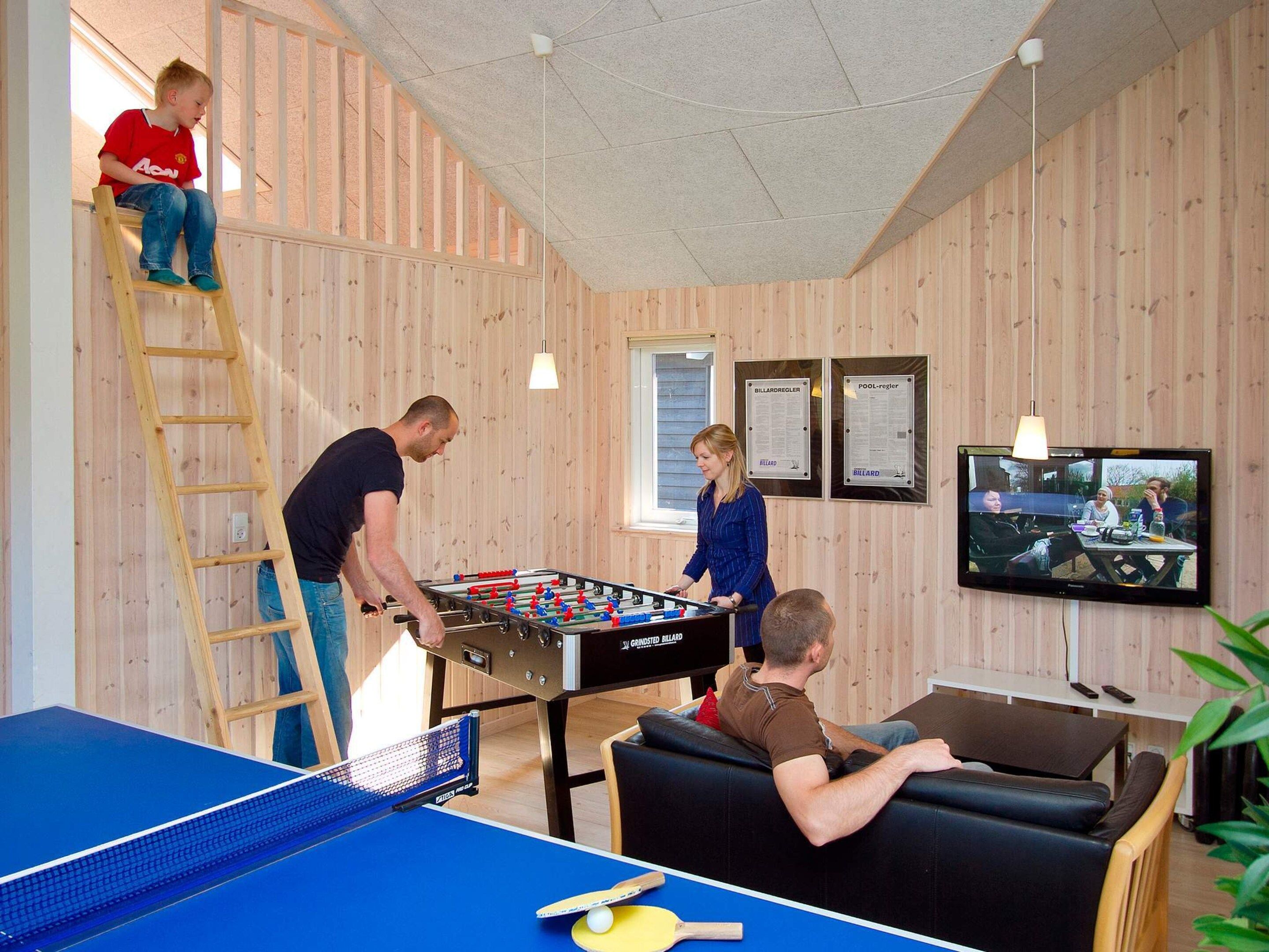 Een kamer met een tafelvoetbaltafel, een pingpongtafel en een biljarttafel.