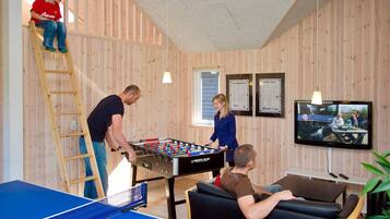 Een kamer met een tafelvoetbaltafel, een pingpongtafel en een biljarttafel.
