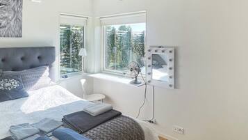 A bedroom with a bed, a window, a vanity with a mirror, and a fan.