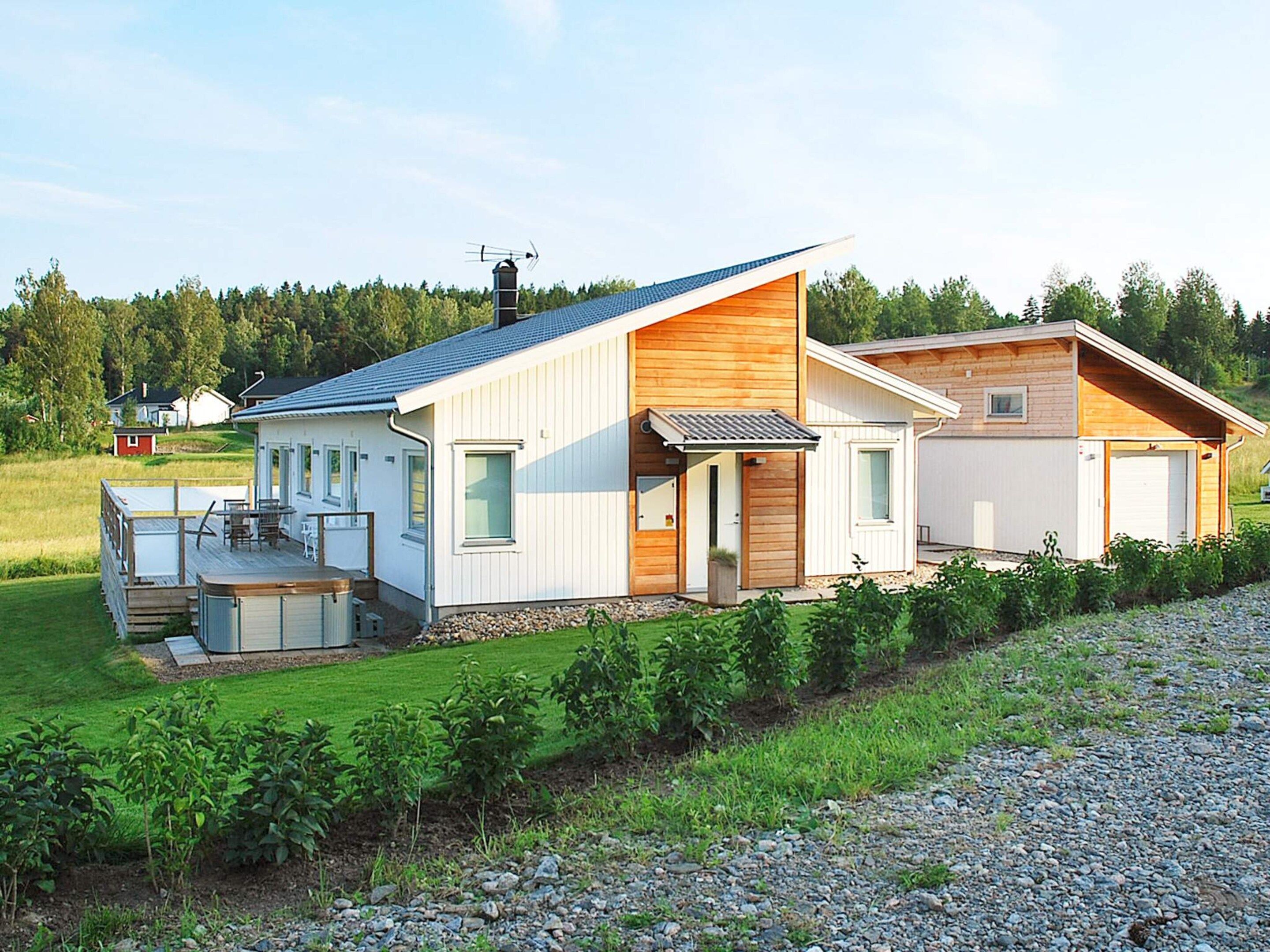 A modern two-story house with a deck, a garage, and a well-maintained lawn.