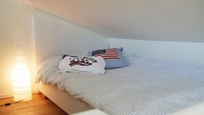 A bedroom with a bed, a lamp, and a pillow with an American flag design. - Holiday Home in Stjärnhov (Stjarnhov)