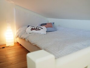 Un dormitori amb un llit, una làmpada i un coixí amb disseny de bandera dels Estats Units.