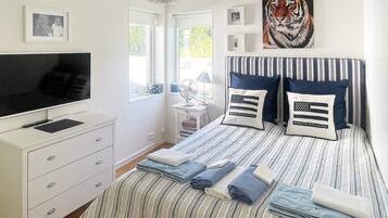 A bedroom with a bed, a TV, a dresser, and a window.