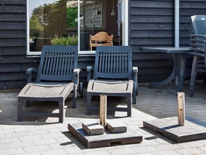 Two outdoor seating areas with chairs and tables, a wooden deck, and a window with a view of greenery. - 5 Star Holiday Home in Sydals (Sydals)