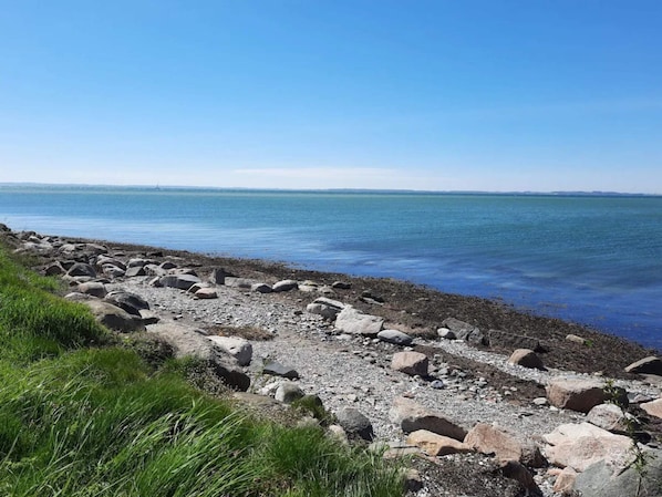 Una costa rocosa con una vista despejada del agua y la tierra distante.