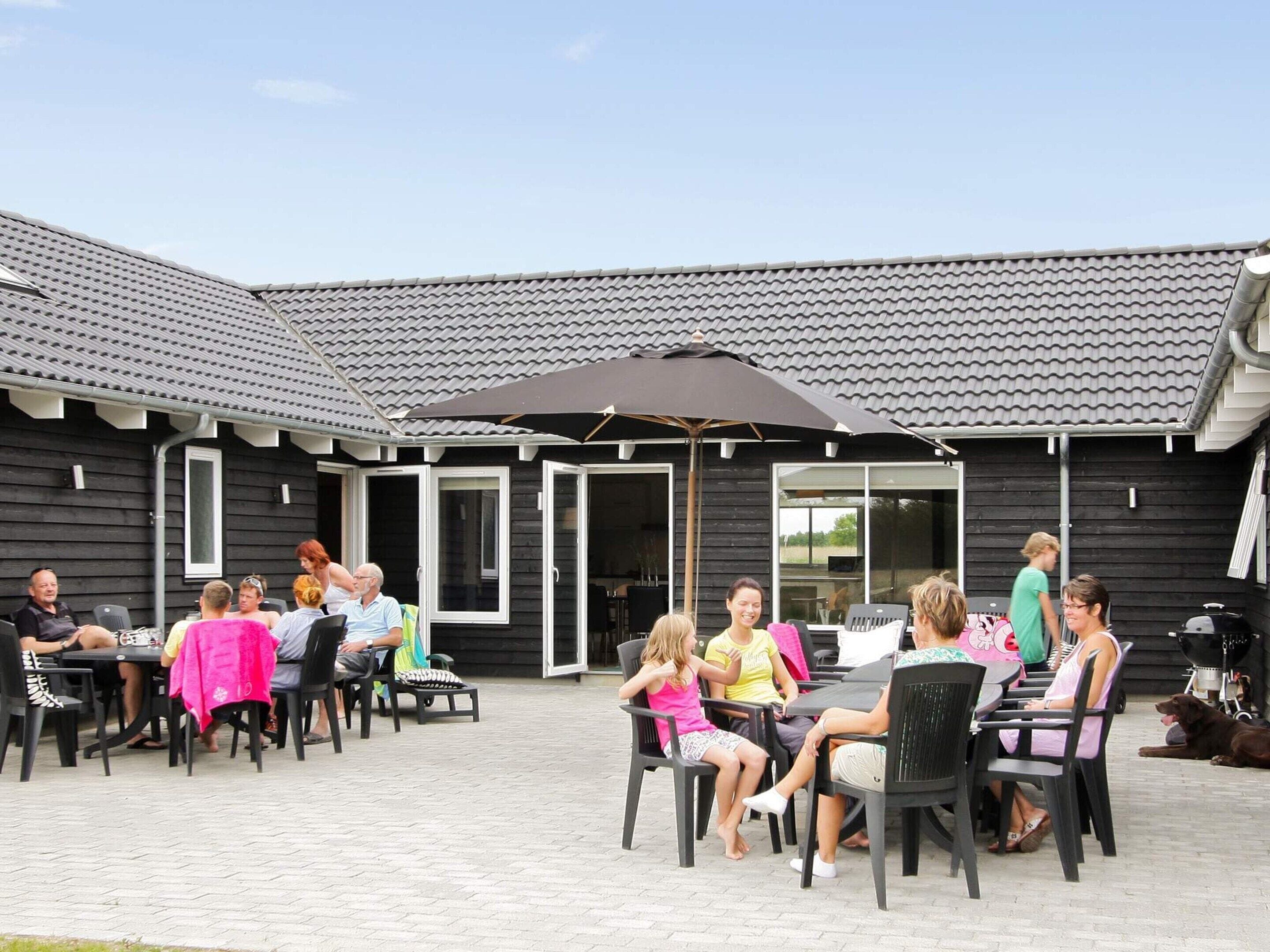 An outdoor patio area with tables and chairs, a covered seating area, and a dog.