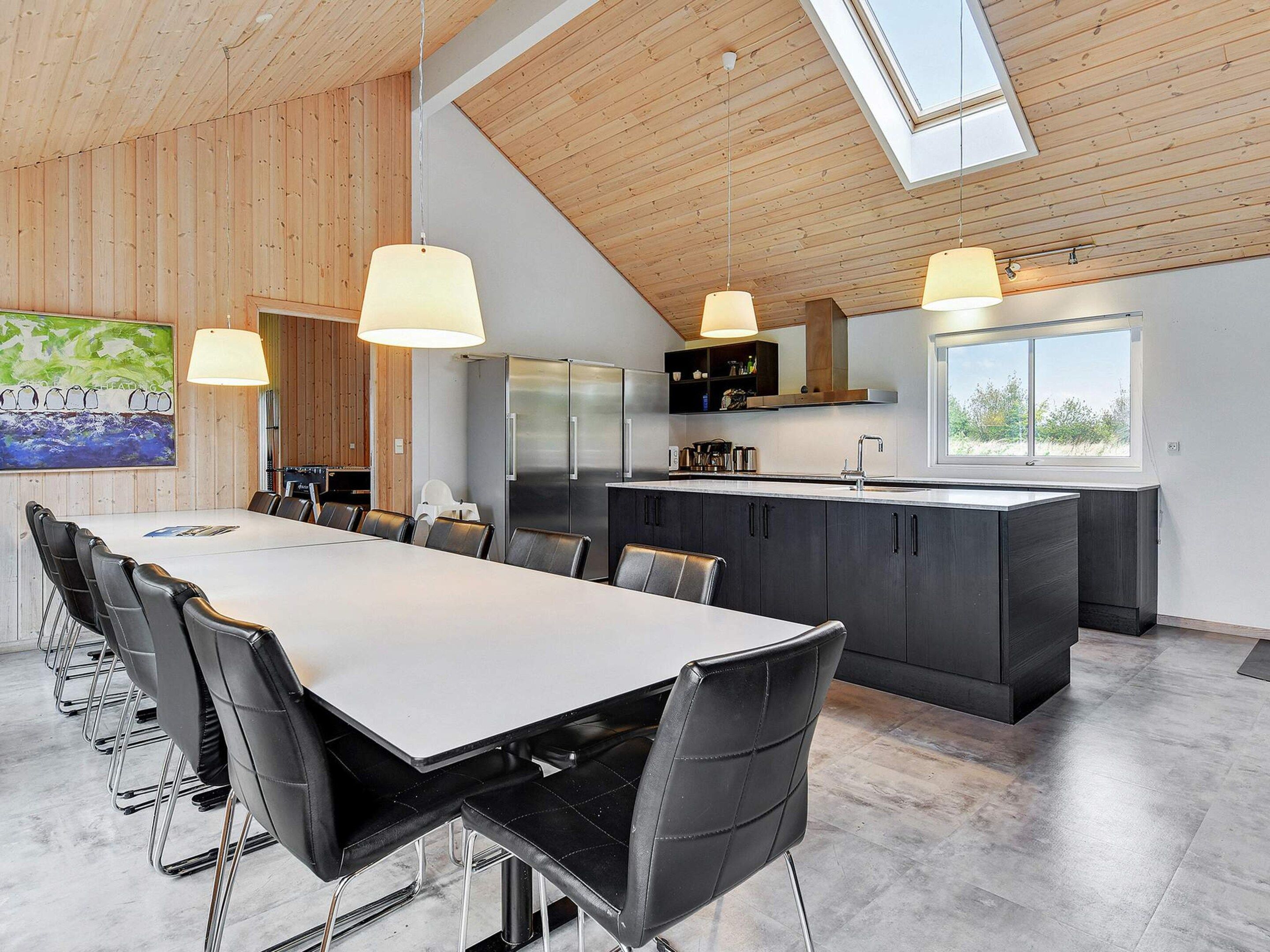 A modern kitchen with a large island, stainless steel appliances, and pendant lighting.