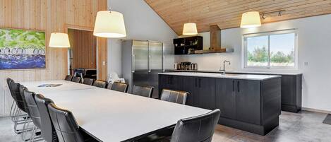 A modern kitchen with a large island, stainless steel appliances, and pendant lighting.