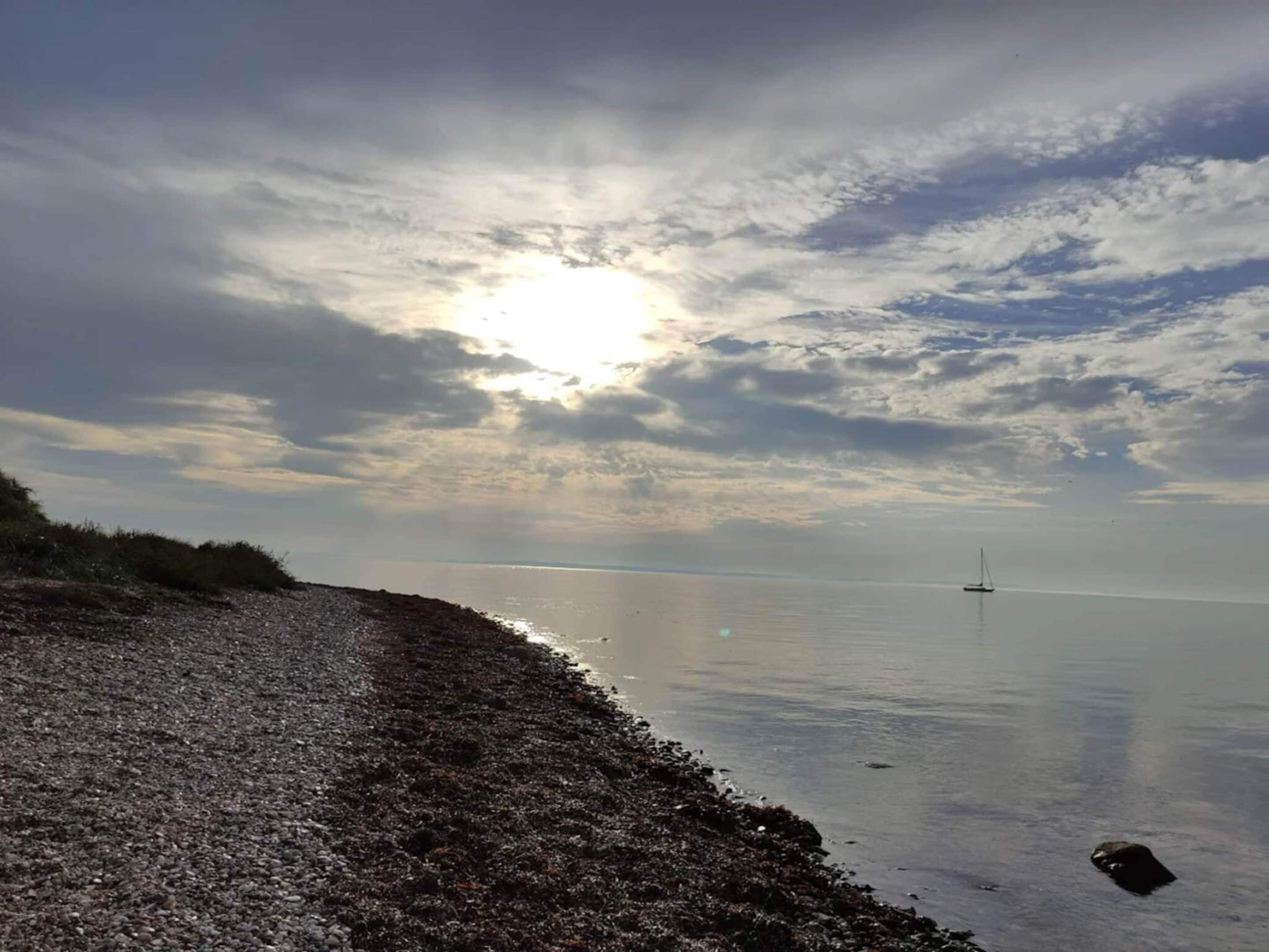 A calm sea with a boat in the distance and a rocky shoreline.