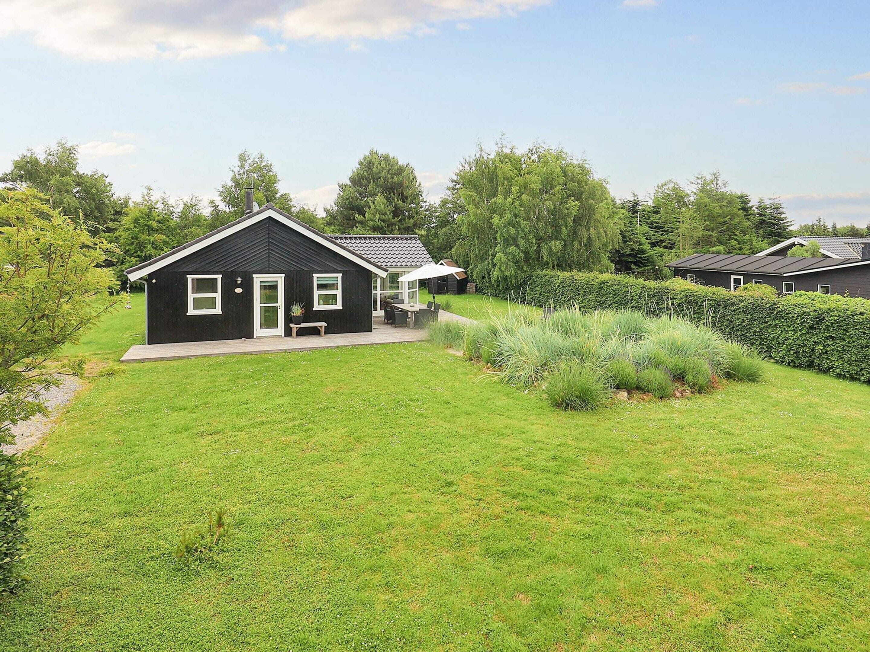 A black house with a porch and a small garden area.