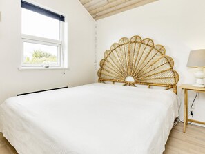 Un dormitorio con cama, ventana y lámpara.