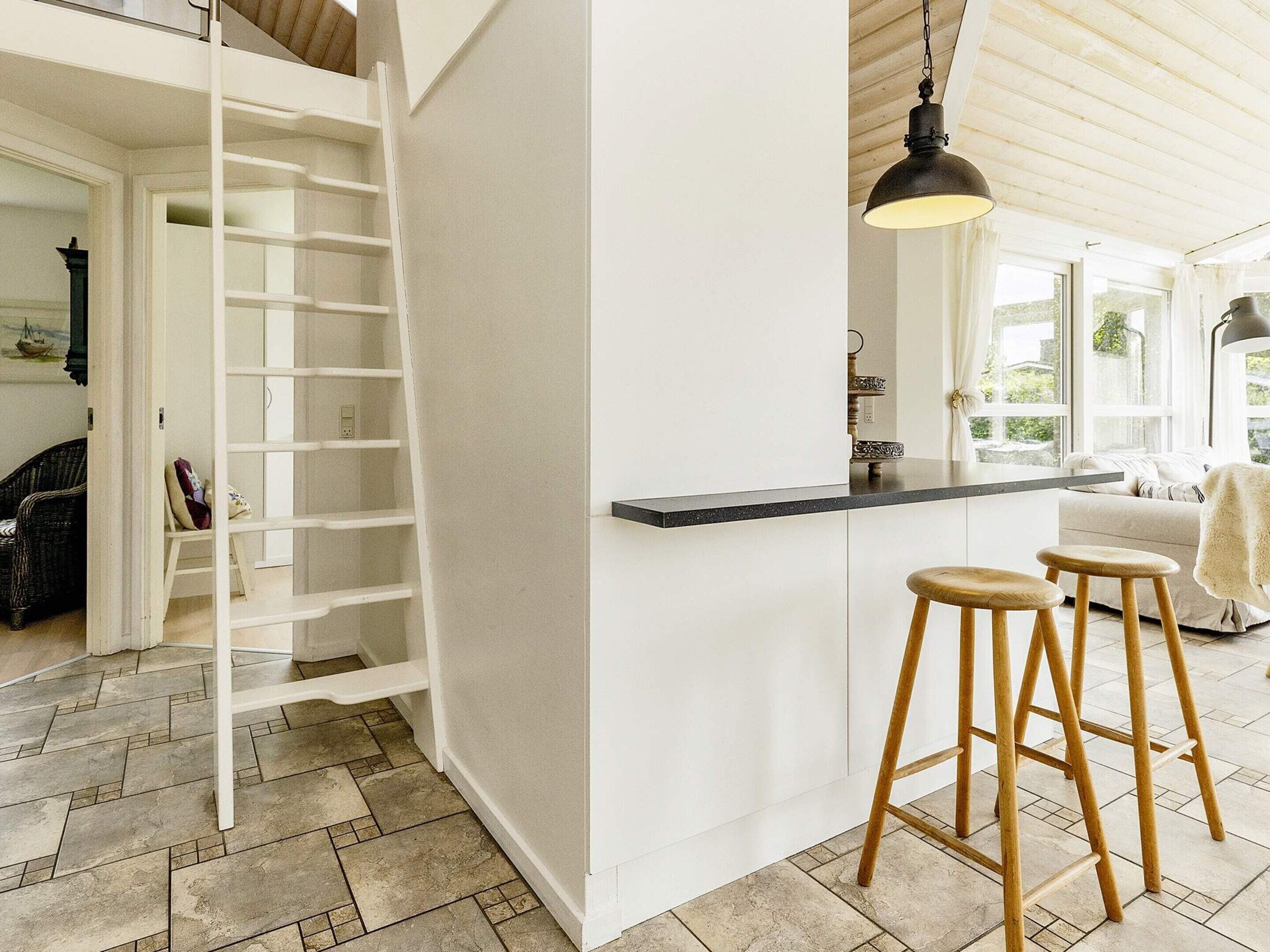 A kitchen with a white interior, a black countertop, and wooden stools.