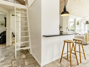 A kitchen with a white interior, a black countertop, and wooden stools.