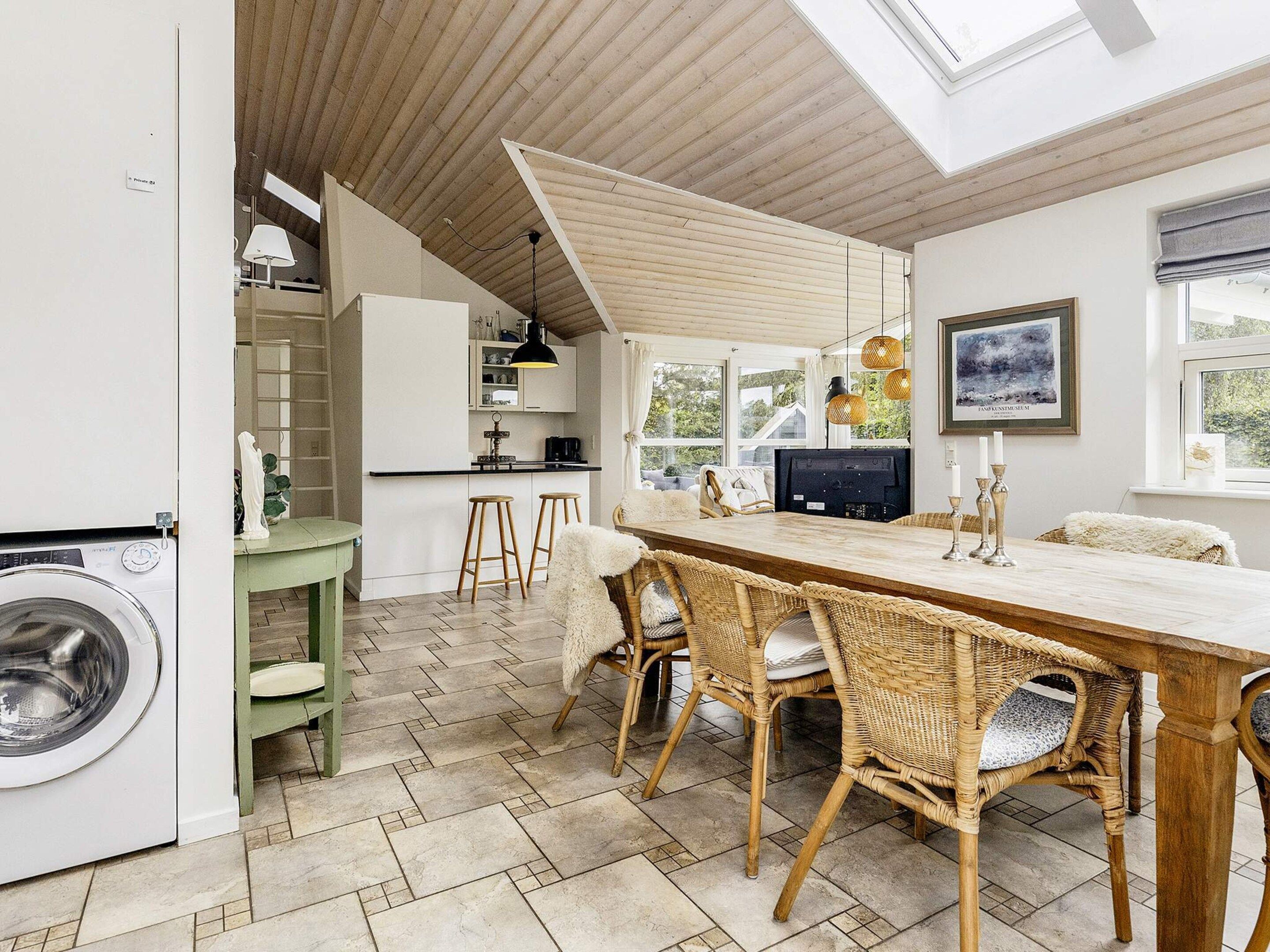 Una cocina moderna con comedor, piso de madera y un ventanal grande.