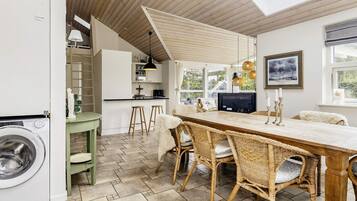 Una cocina moderna con comedor, piso de madera y un ventanal grande.