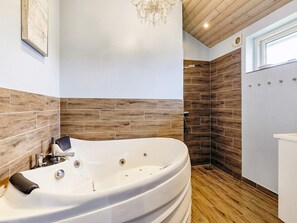 Une salle de bain moderne avec une baignoire sur pieds, des carreaux de mur en bois et un lustre.