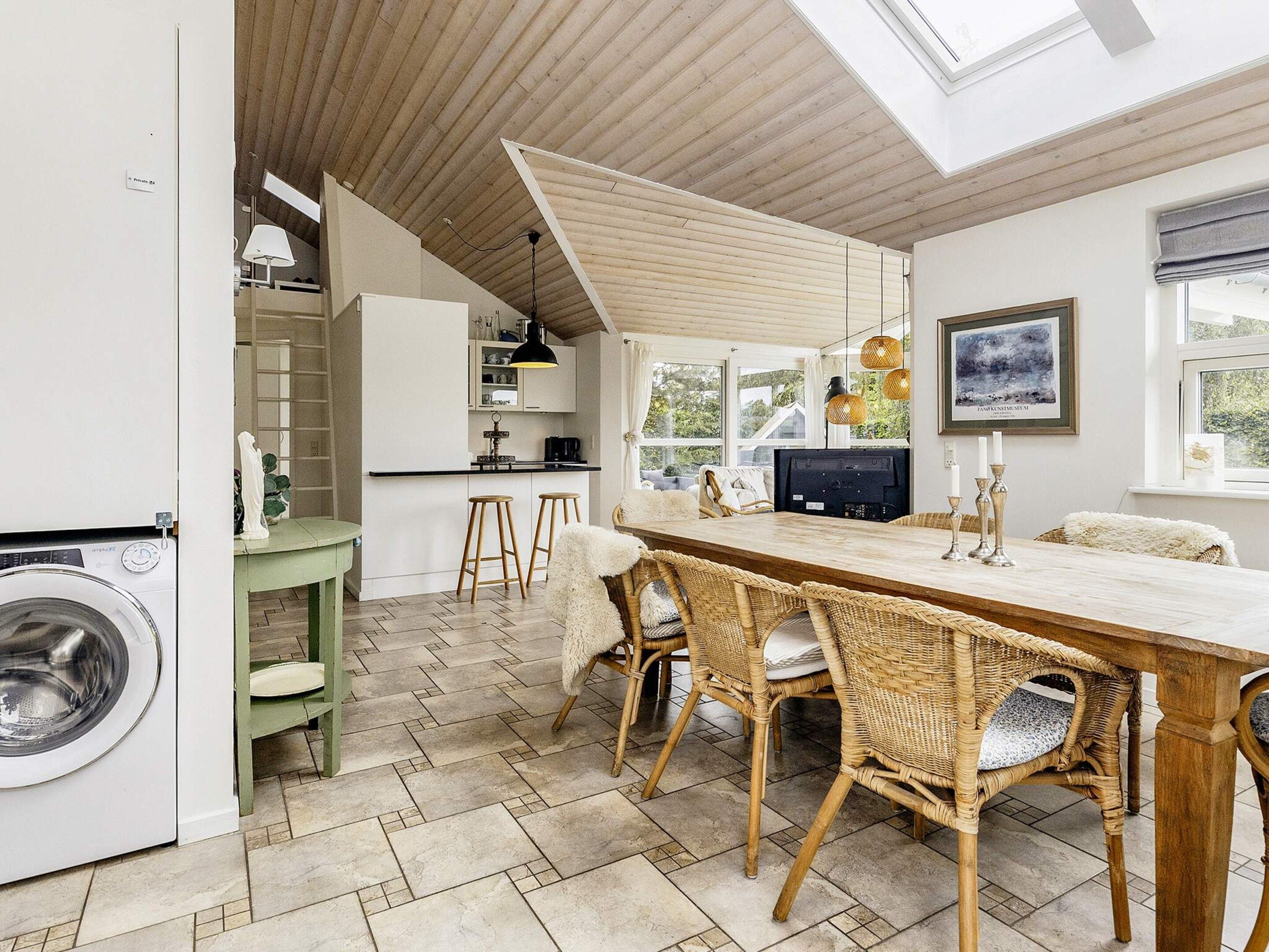 A modern kitchen with a dining area, a washing machine, and a large window.