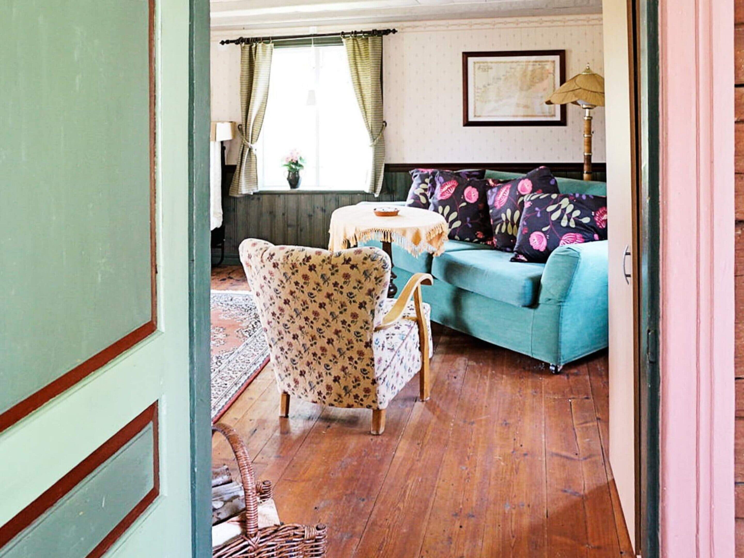 A living room with a blue sofa, floral armchairs, a round table, and a lamp.