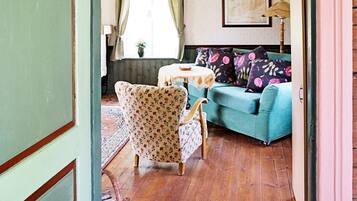 A living room with a blue sofa, floral armchairs, a round table, and a lamp.