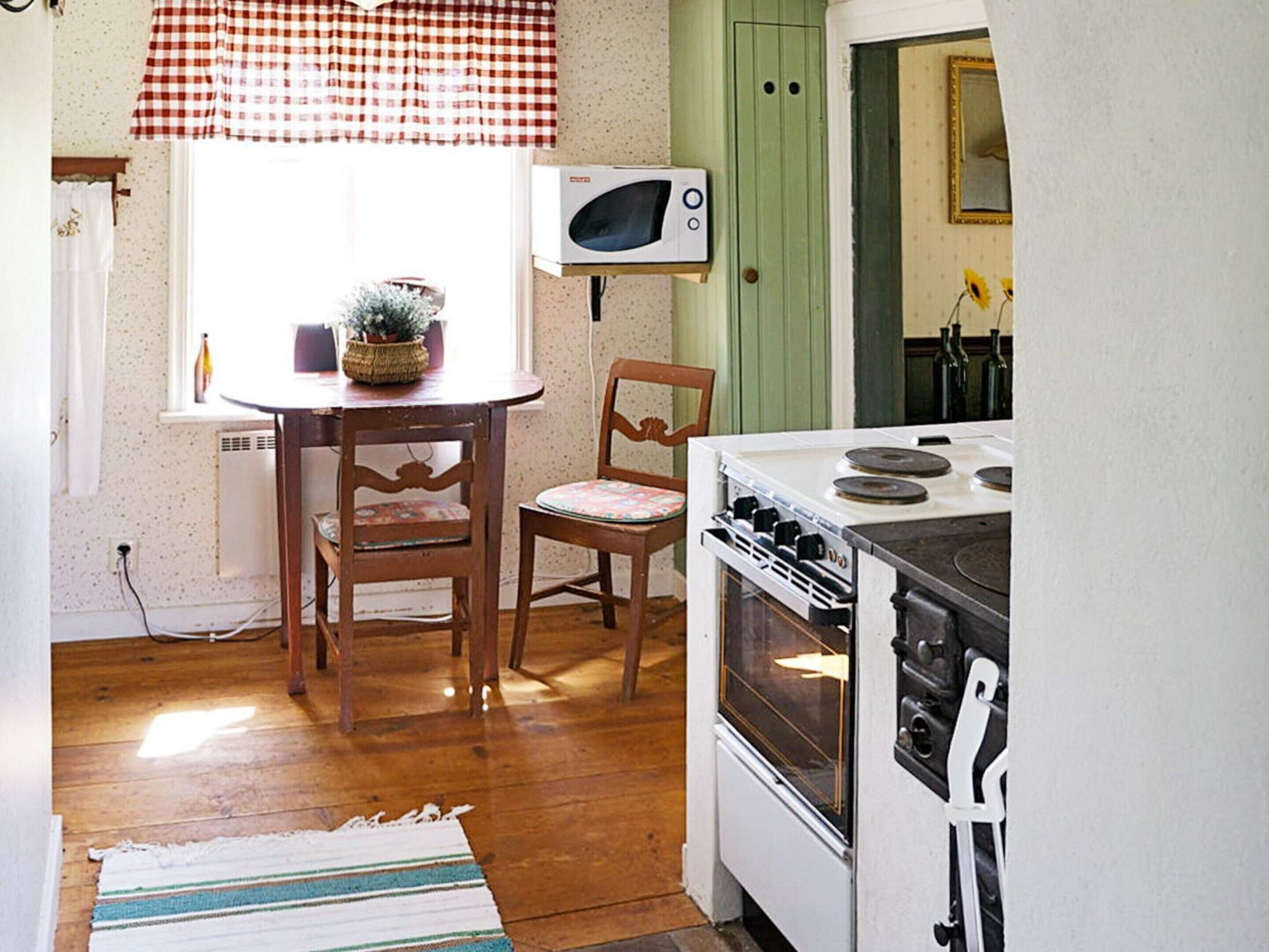 Une cuisine équipée d’une cuisinière, d’un four à micro-ondes et de chaises en bois.
